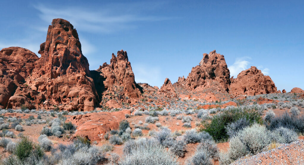 Red rock formations rugged desert bushes clear blue sky vibrant arid landscape wallpaper background