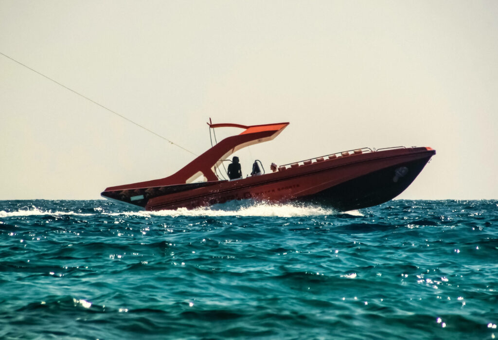 Red speed boat gliding on vibrant blue ocean waves under clear sky sailing wallpaper background