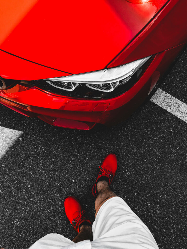 Top view of red sports car and person with red shoes on dark asphalt dynamic wallpaper background