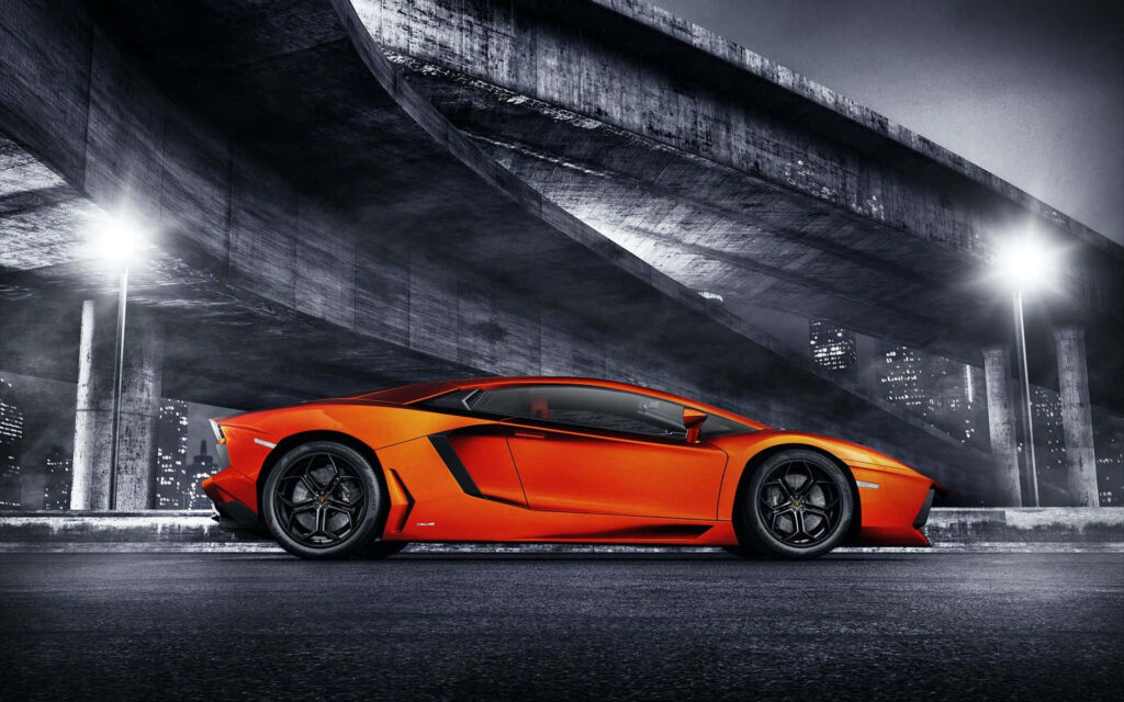 Red sports car parked on open road under modern overpass with city nightscape and streetlights Wallpaper