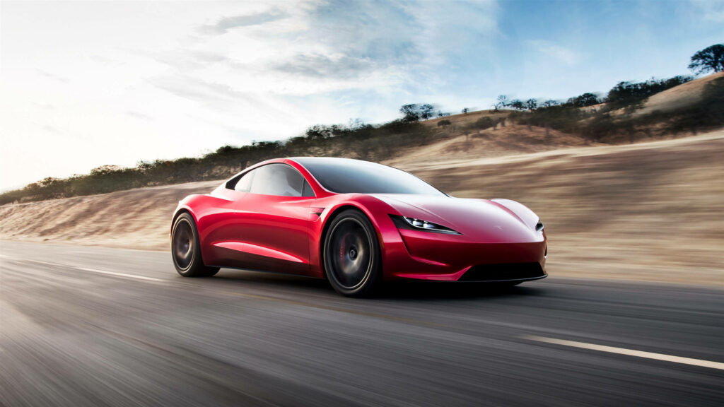 Red Tesla Roadster speeding on open road with rolling hills and clear blue sky background Wallpaper