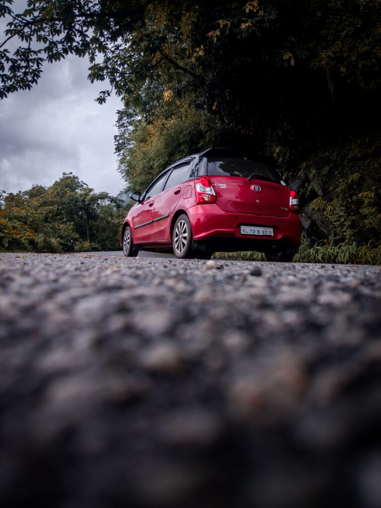 Red Toyota Etios Rear View Wallpaper on Scenic Green Road