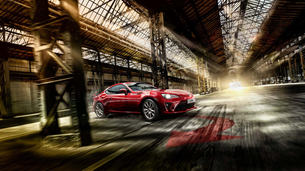 Red Toyota FT-1 sports car speeding inside sunlit industrial warehouse 4K wallpaper background