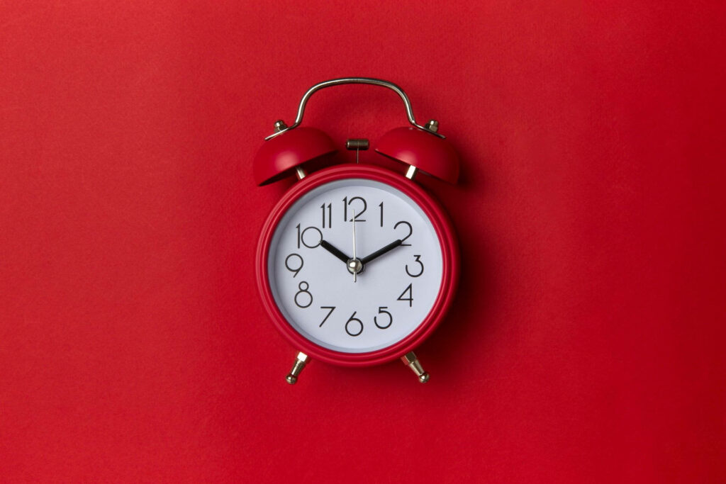 Classic red twin bell alarm clock on vibrant red background minimalist monochrome wallpaper