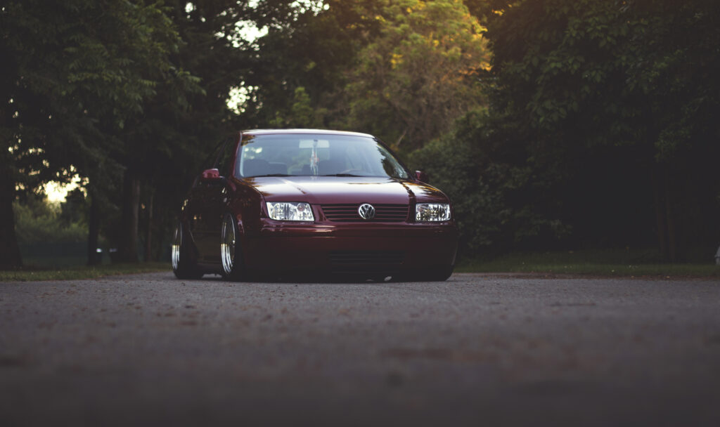 Front View of Red Volkswagen Jetta in Serene Tree-Lined Setting Wallpaper