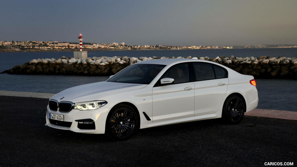 Majestic Oceanfront Drive: Nighttime Glamour with BMW's Classic White M Series Wallpaper
