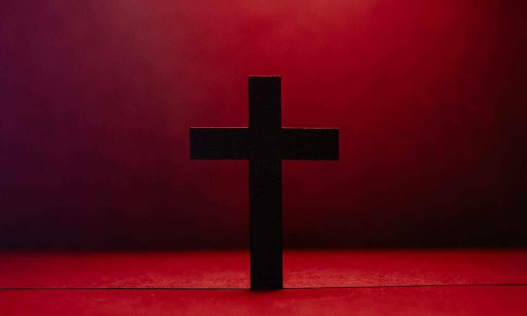 Sacred Symbolism: The Black Christian Cross Wallpaper in a Bold Red Background