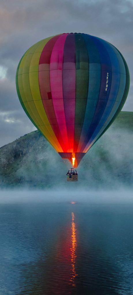 Colorful hot air balloon with orange flame over misty lake serene Redmi Note 10 wallpaper background