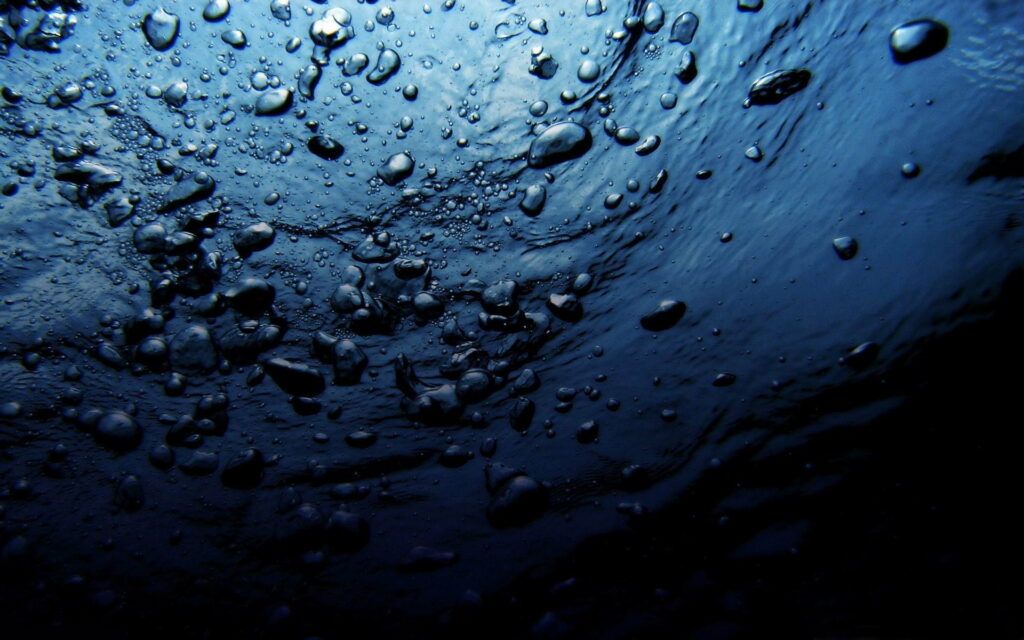 Tranquil underwater wallpaper with rising air bubbles and deep blue light refraction background