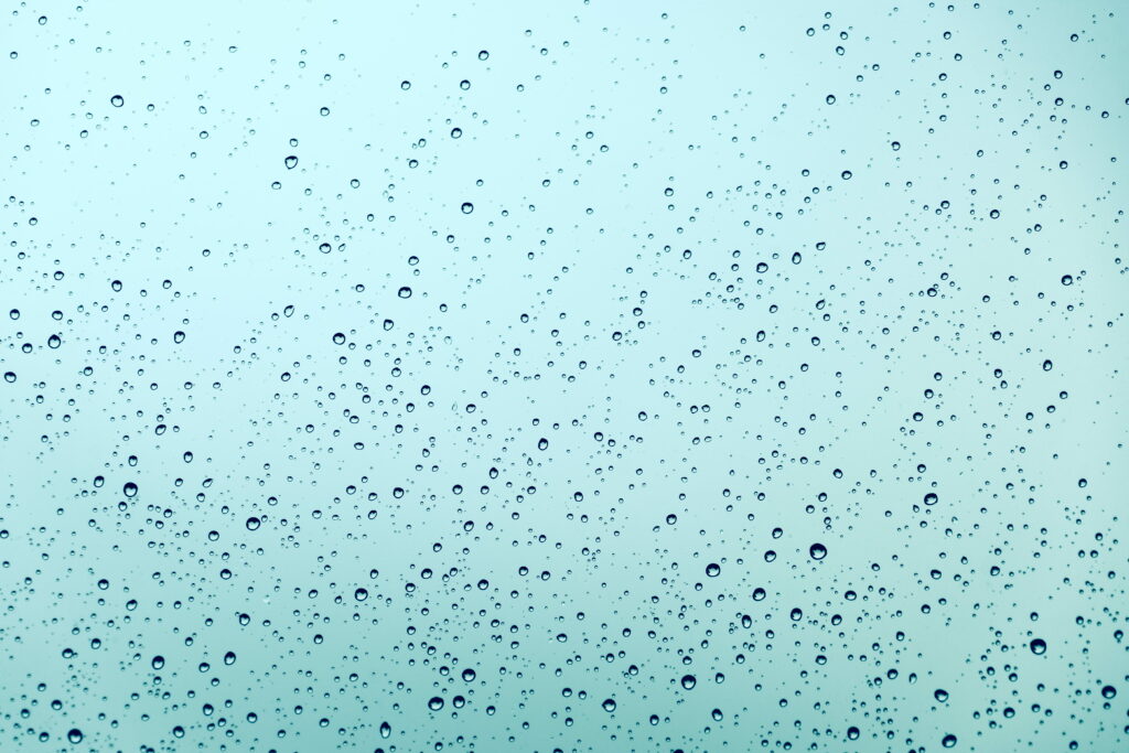 Close-up of delicate water droplets on light blue surface abstract minimalist rainy wallpaper background
