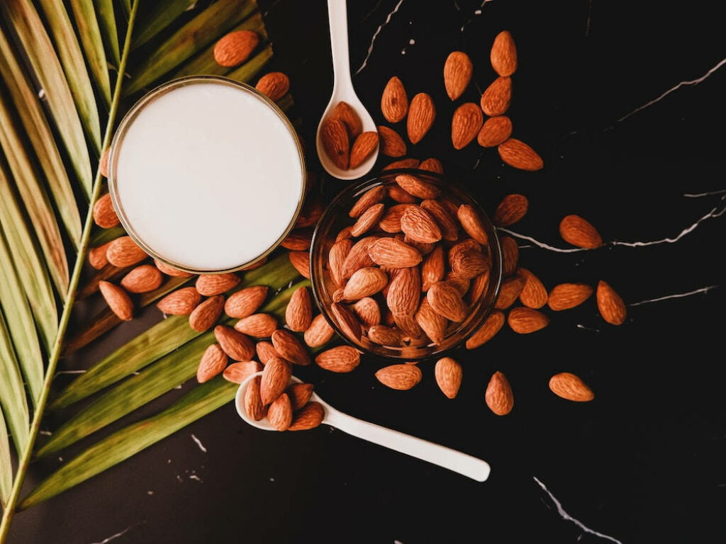 Fresh Almond Milk Wallpaper with Whole Nuts and Green Leaves