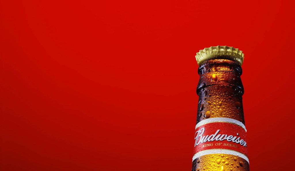 Close-up of cold Budweiser beer bottle with condensation on red background King of Beers Wallpaper
