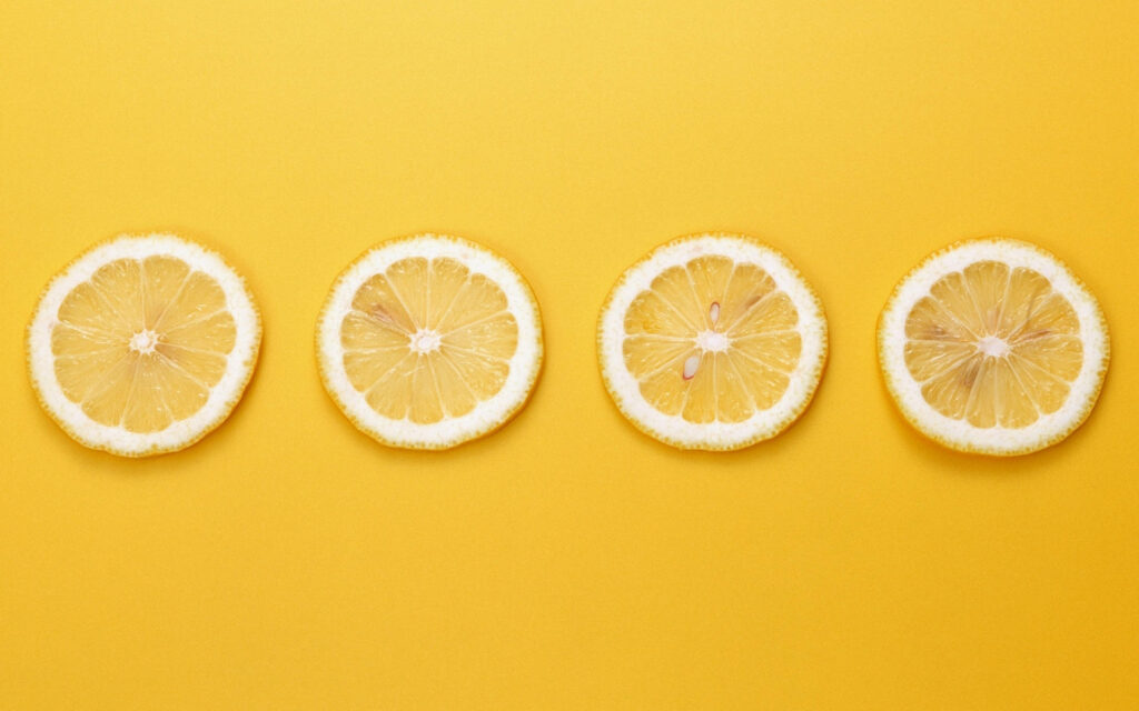 Vibrant Lemon Slice on Yellow-Orange Minimalist Background Wallpaper