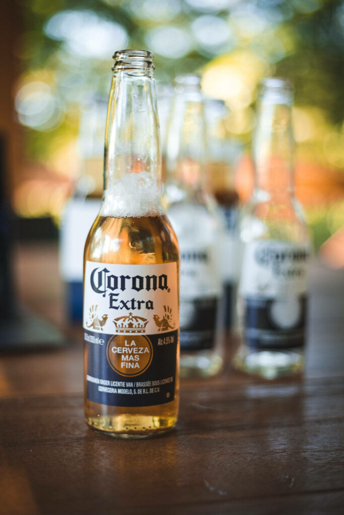 Crisp Corona Extra beer bottle on wooden table with warm light and blurred background bottles Wallpaper
