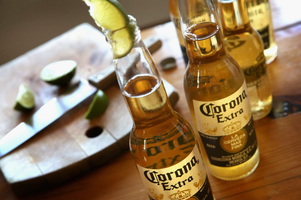 Corona Extra beer bottles with lime slices on rustic wood summer wallpaper background