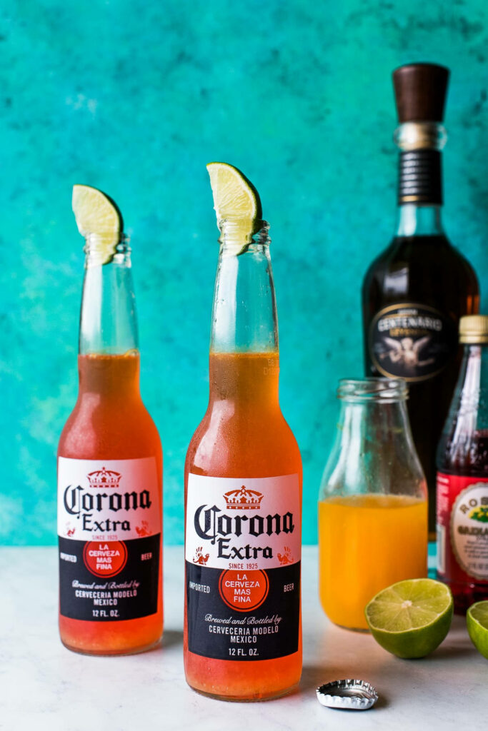 Two Corona Extra bottles with lime wedges on turquoise background festive summer wallpaper