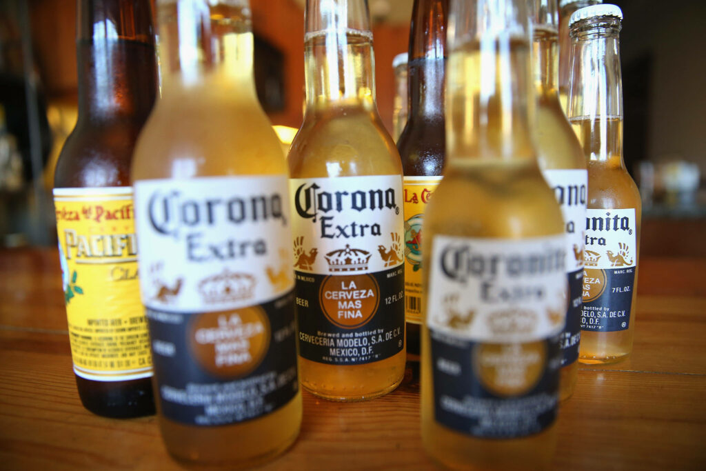 Chilled Corona Extra and Pacifico Clara beer bottles on wood with sunlit condensation background Wallpaper
