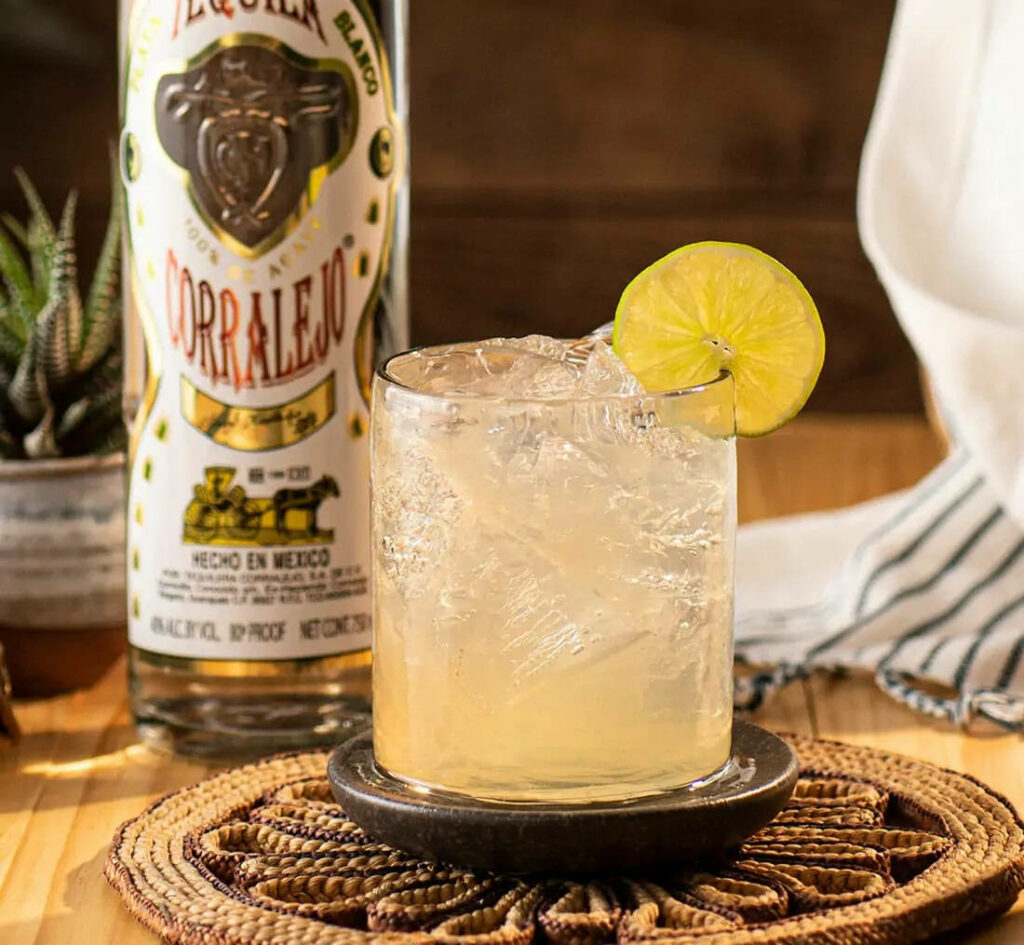 Refreshing Corralejo Tequila Blanco lemon cocktail with lime garnish on rustic wooden background Wallpaper
