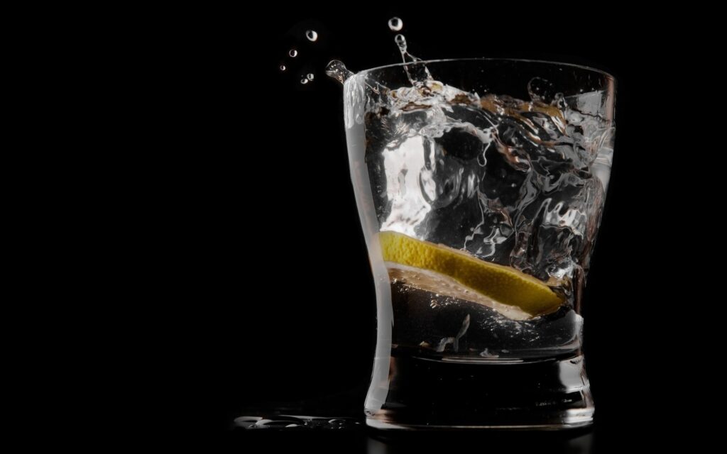 Refreshing Wallpaper: Lemon Ice Beverage Splash on Dark Background
