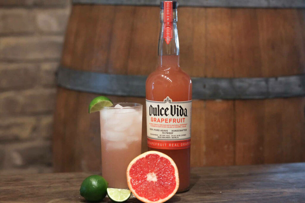 Chilled Dulce Vida Grapefruit Texas Cocktail with ice lime fresh citrus on rustic wooden barrel Wallpaper