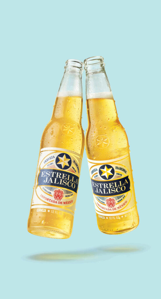 Two chilled Estrella Jalisco beer bottles clinking with condensation on light blue background Wallpaper