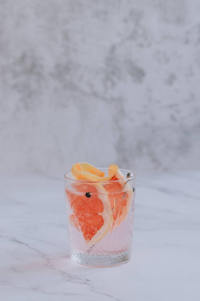 Gin cocktail wallpaper with grapefruit slices juniper berries on marble summer mood background
