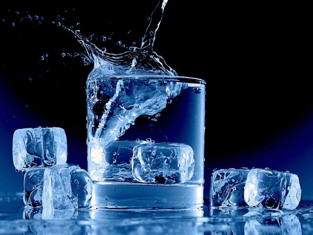 High-speed splash of water and ice in glass with cool blue lighting on dark background wallpaper