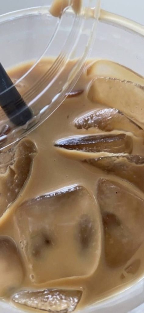 Close-up iced coffee with clear ice cubes black straw in bright natural light wallpaper background