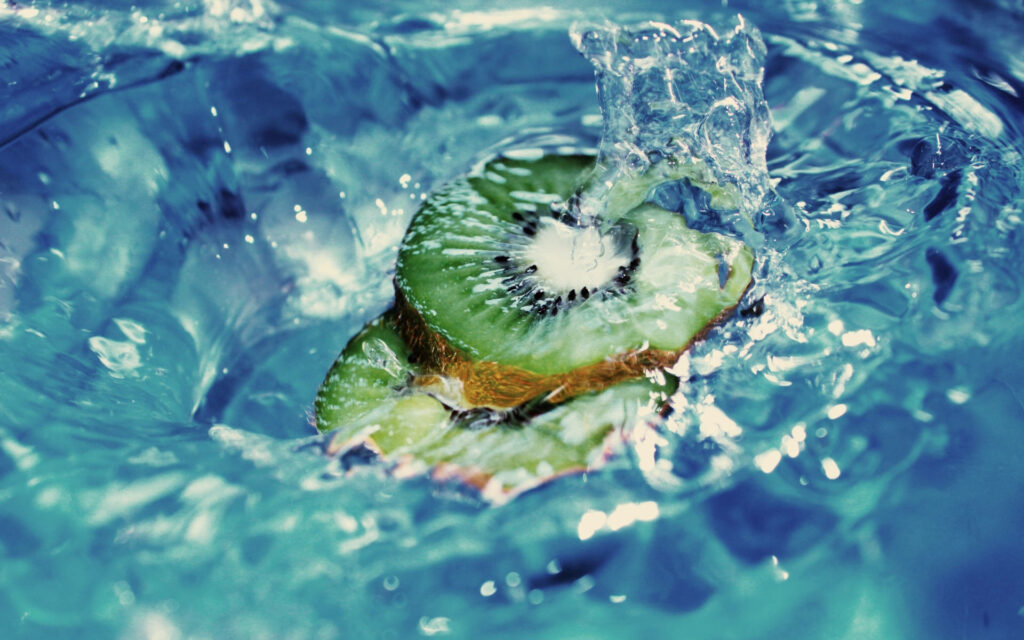 Close-up of juicy kiwi fruit splashed with fresh water vibrant refreshing wallpaper background
