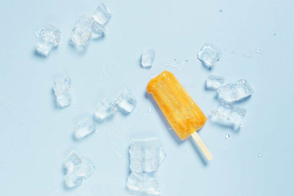 Cool Orange Popsicle Wallpaper with Ice Cubes on Light Blue Background