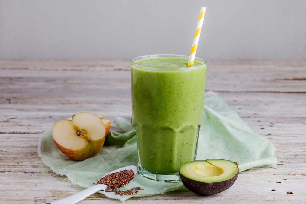 Refreshing Avocado Smoothie with Colorful Fruit Accents on Rustic Wooden Table Wallpaper