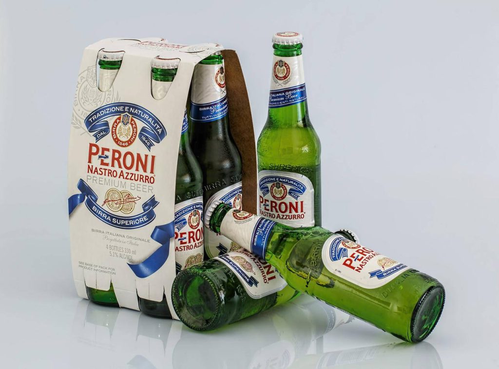 Studio photo of Peroni Nastro Azzurro beer with green bottles and cardboard carrier on white background Wallpaper