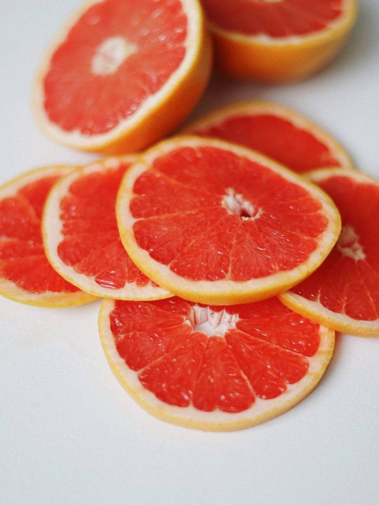 Vibrant grapefruit slices piled on white background fresh juicy citrus wallpaper background