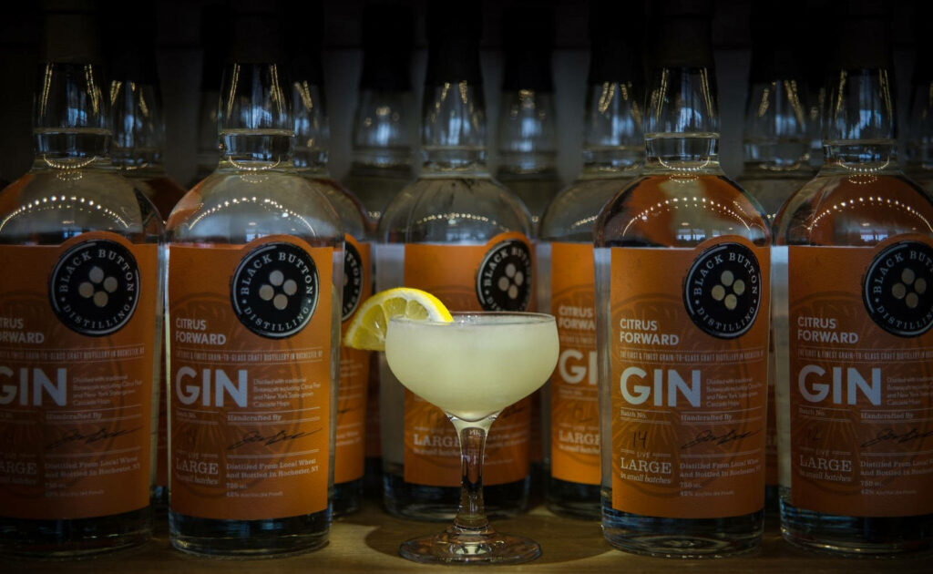 Saturn cocktail with lemon wedge and Black Button Citrus Forward Gin bottles in stylish bar setting Wallpaper