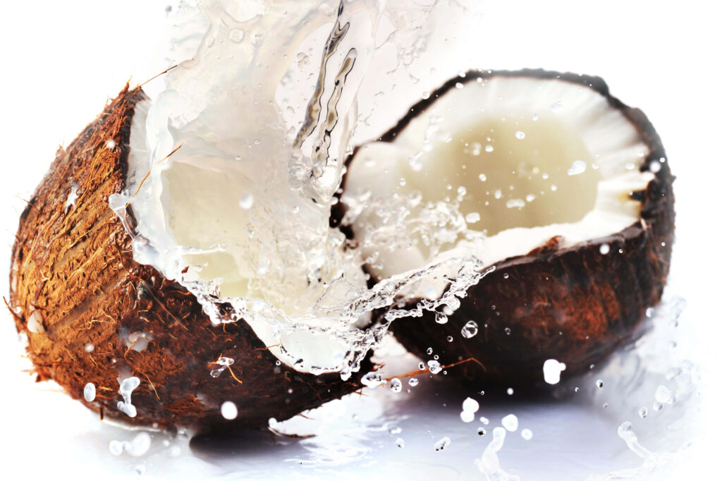 Fresh split coconut with clear water splash vibrant texture on white background wallpaper