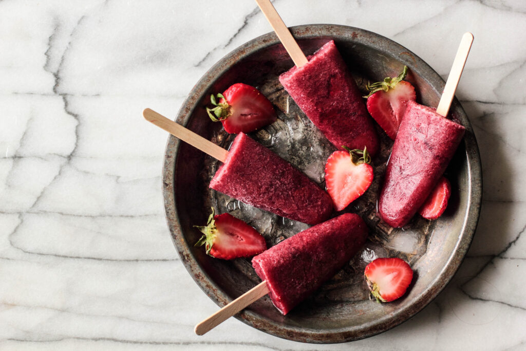 Vibrant Strawberry Popsicle Wallpaper on Ice with Fresh Slices
