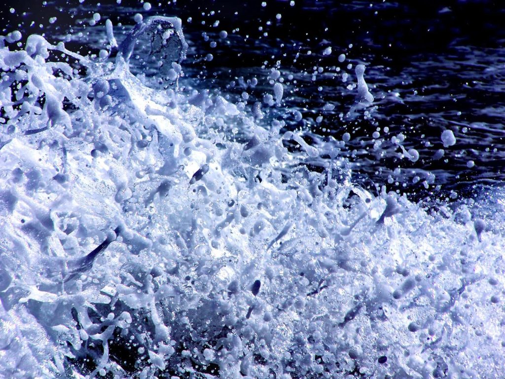 High contrast ocean waves splash bright white foam over deep blue turbulent sea summer wallpaper
