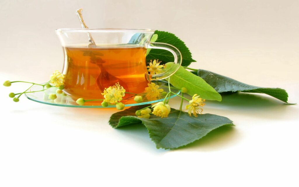Elegant Tea Cup Wallpaper: Soothing Nature with Green Leaves & Flowers