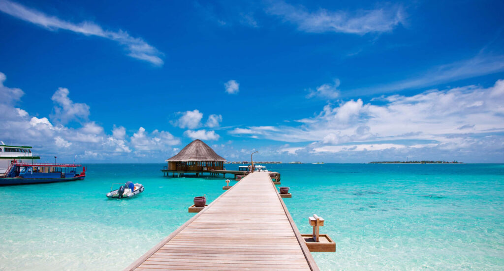 Serene Beach Scene: Wooden Pier & Hut Over Turquoise Waters Wallpaper
