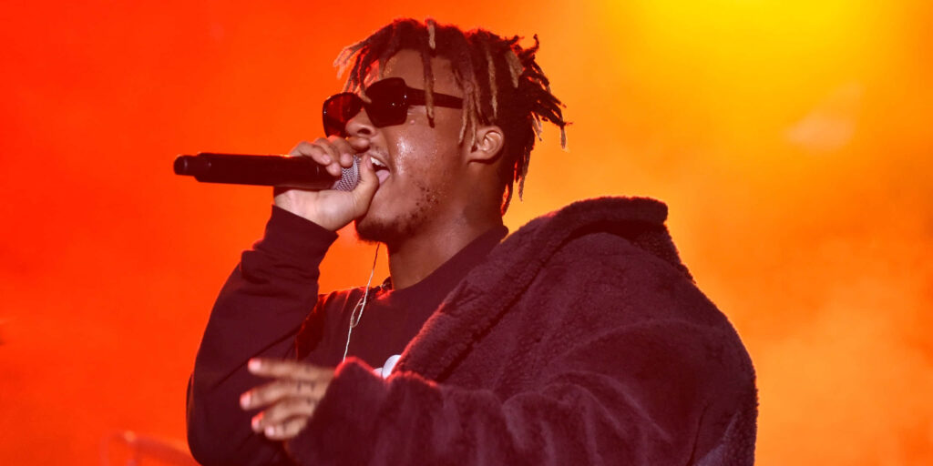 Juice WRLD concert wallpaper with vibrant orange lights and artist in sunglasses and black jacket