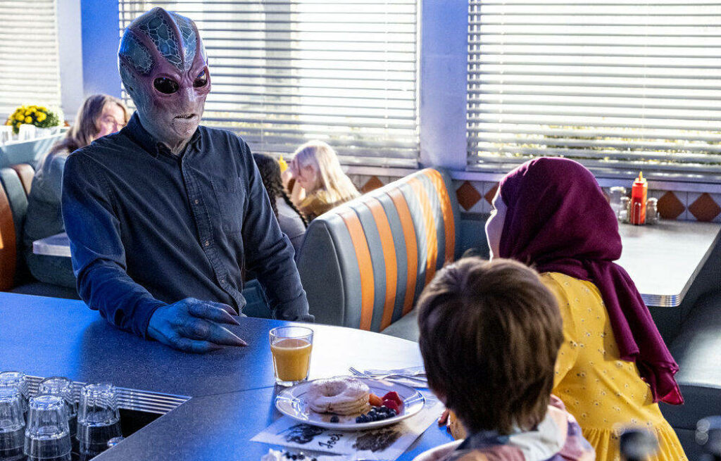 Resident Alien: Restaurant Scene with Alien Character - Wallpaper