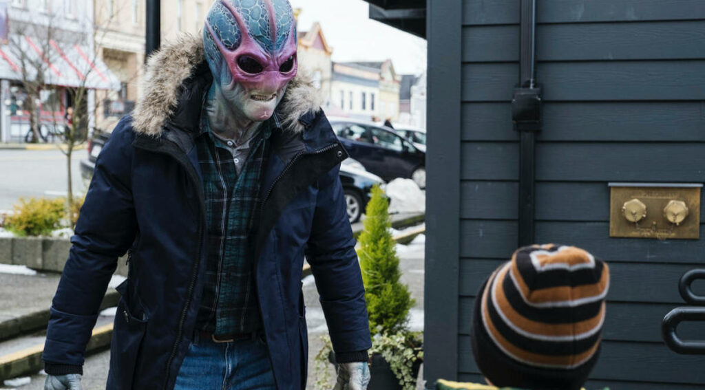 Alien in Winter Coat Engages with Child in Snowy Resident Alien Scene Wallpaper