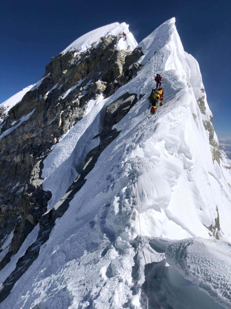 Resilient Climbers on Snowy Mountain Peak - Stunning Wallpaper Background
