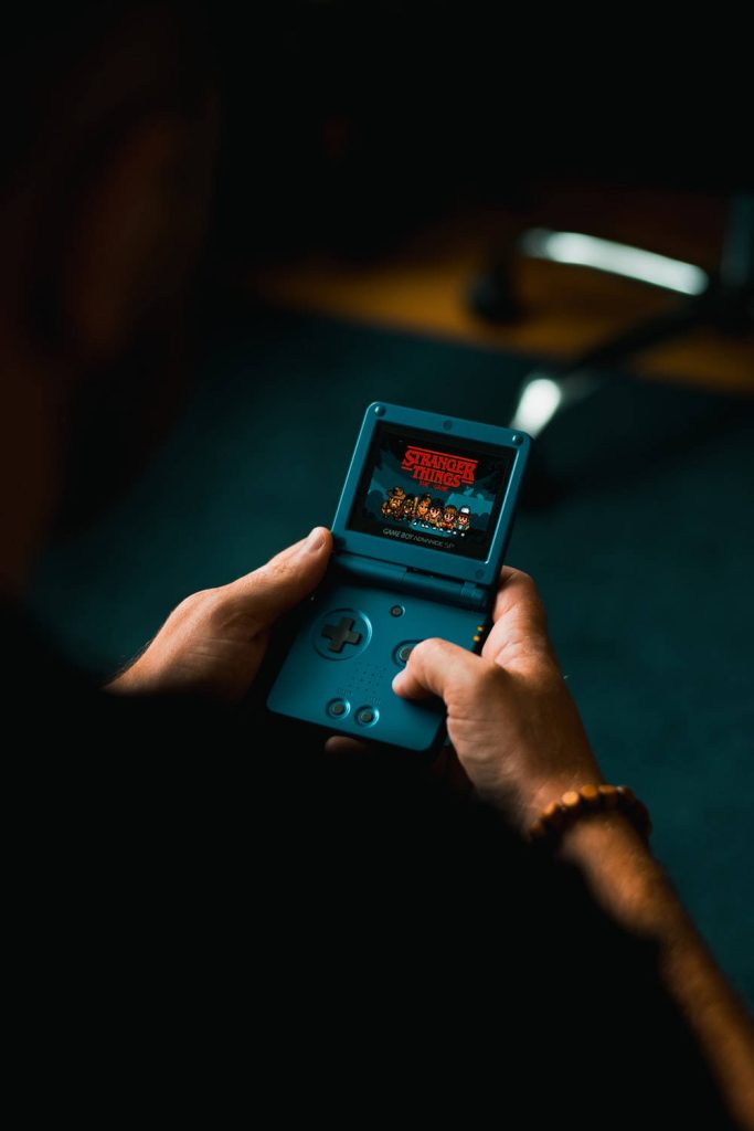 Teal Game Boy Advance SP showing Stranger Things The Game pixel art retro handheld wallpaper