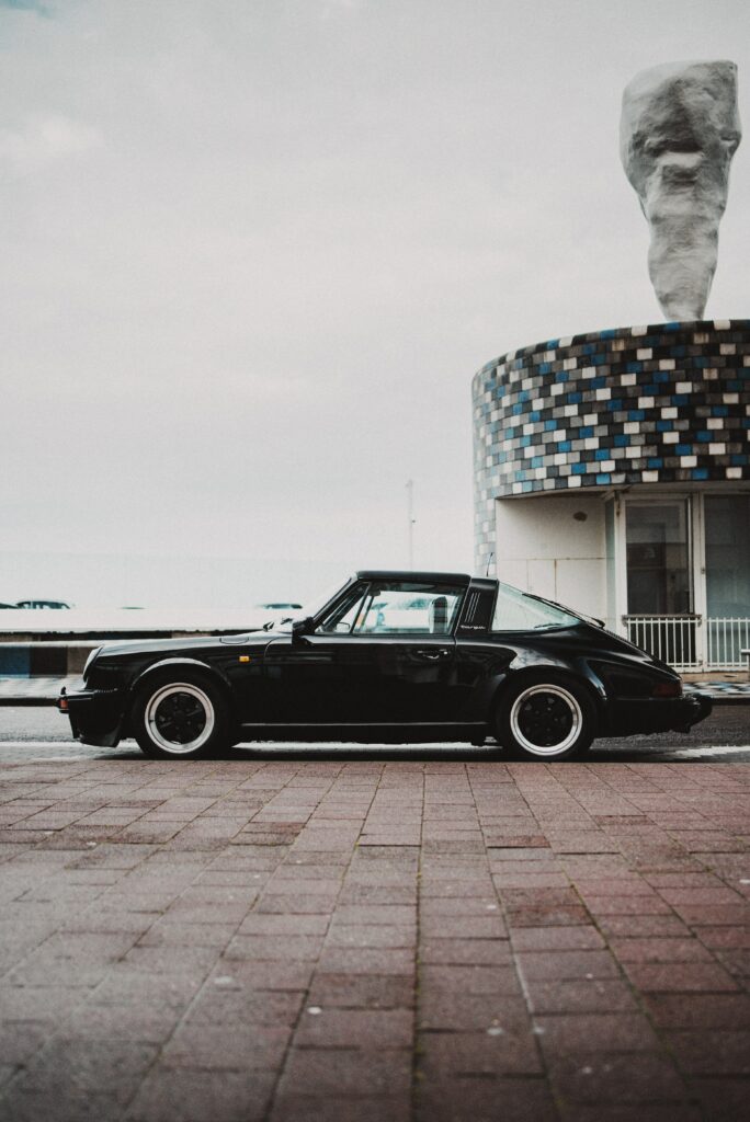 Retro Black Car & Mosaic Building: Striking Visual Contrast Wallpaper