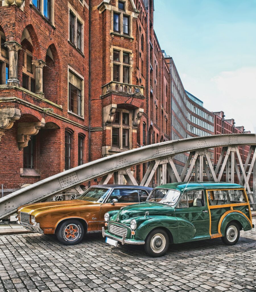 Retro Cars on Cobblestone Street with Red Brick Building Background Wallpaper
