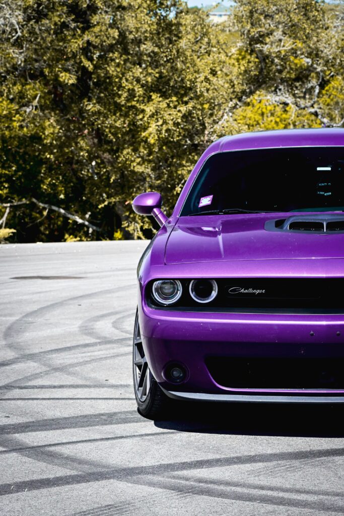 Retro Challenger Car Wallpaper: Bold Purple Against Greenery & Asphalt