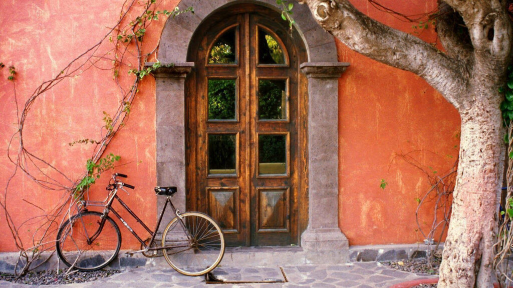 Nostalgic Charm: A Vintage Bicycle Rests by an Old Orange Home Wallpaper
