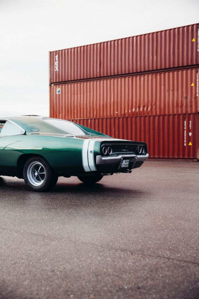 Retro Green Dodge Charger Against Shipping Containers - Vintage Charm Wallpaper