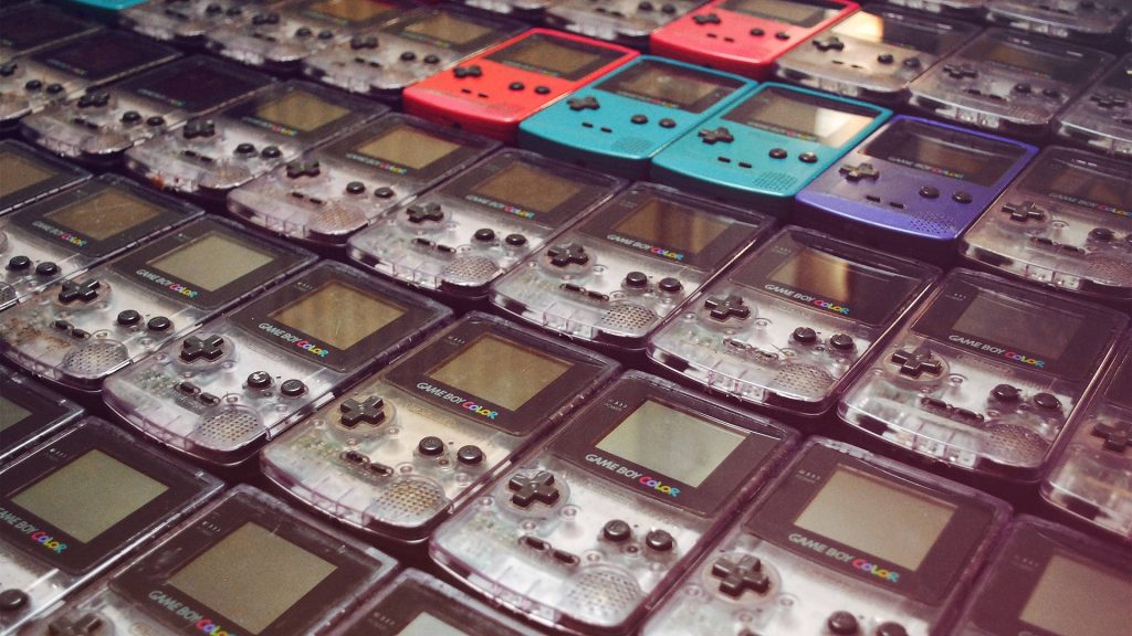 High-angle view of colorful classic Nintendo Game Boy Color consoles in neat rows vintage wallpaper